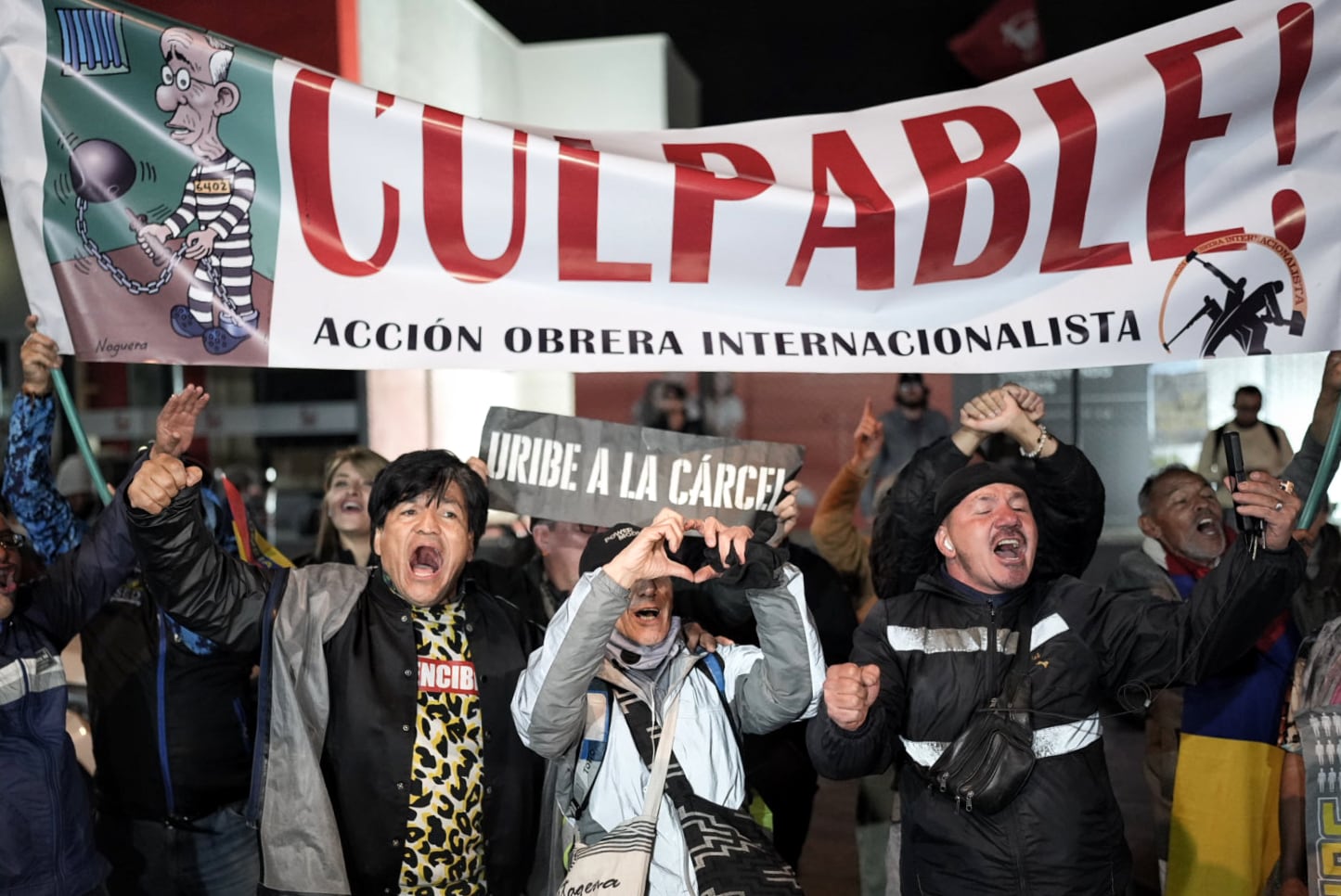 Detractores de Álvaro Uribe celebran la condena al exmandatario colombiano, afuera de los juzgados de Paloquemao, en Bogotá.