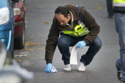 Un policía recoge un casquillo en el escenario del crimen.