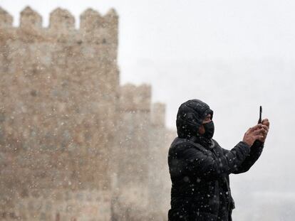 Un vecino se hace un 'selfie' junto a las murallas de Ávila mientras nieva, este lunes.
