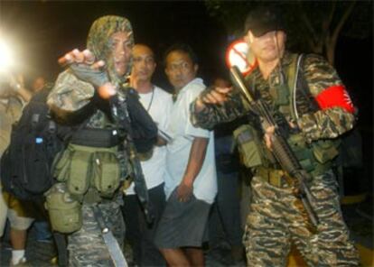Dos soldados filipinos vigilan el exterior del edificio donde se refugian los amotinados.