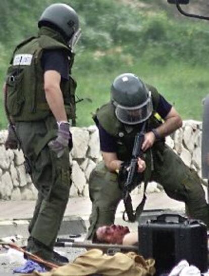 Un policía apunta al hombre que llevaba la bomba que estalló ayer en Israel.