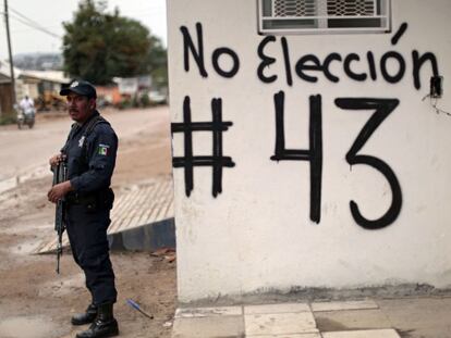 Policial em Guerrero (México) ao lado de pichação pelo boicote eleitoral.