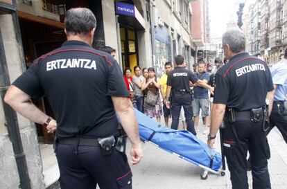 Dos 'ertzainas' supervisan la retirada del cadáver de una mujer en su domicilio en Bilbao, asesinada a manos de su pareja.