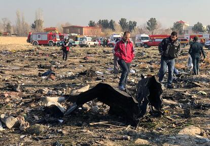Varias personas, junto a los restos del avión siniestrado cerca de Teherán (Irán), este miércoles.