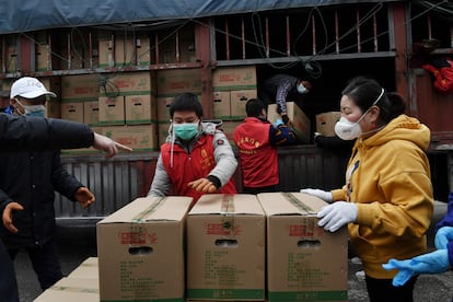 Un grupo de voluntarios descarga alimentos para un complejo de viviendas en Wuhan, el foco de la epidemia de coronavirus.