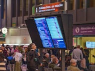 Varios viajeros consultan información sobre los horarios de trenes en el vestíbulo de la estación de Santa Justa de Sevilla.
