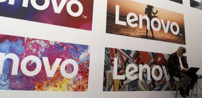 Un hombre utiliza un ordenador portátil junto a logos de Lenovo en el último Movile World Congress.