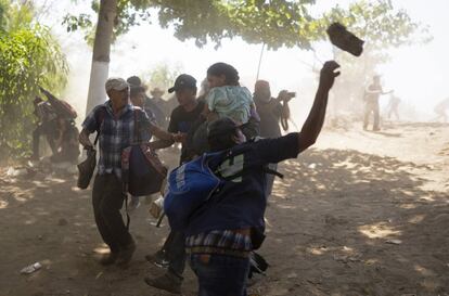 Um migrante joga uma pedra contra membros da Guarda Nacional depois de atravessar o rio Suchiate a partir da Guatemala.