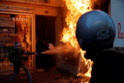 Una persona intenta apagar un cartel publicitario incendiado, en la manifestación de París.