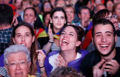 Varios jóvenes aplauden durante el seguimiento de la comparecencia de Carles Puigdemont a través de una pantalla gigante situada en el lugar de la concentración a favor de la independencia.
