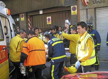 Sanitarios del Samur y bomberos trasladan al herido al interior de una ambulancia.