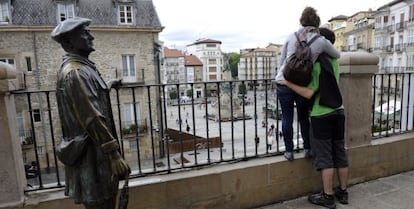 Dos jóvenes se asoman a la balconada de San Miguel, en Vitoria, junto a la escultura que rinde homenaje a Celedón.