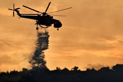 Un helicóptero descarga agua anoche sobre el incendio forestal que se ha producido en el área de Agioi Theodoroi, en las afueras de la ciudad de Corinto, en el Peloponeso. 