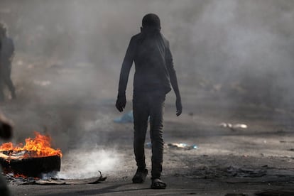 Apesar do apelo do Governo, as escolas permanecem fechadas no Haiti depois de quase duas semanas de protestos e manifestações. Um rapaz cobre o rosto ao passar por uma barricada em chamas durante os protestos em Porto Príncipe, em 17 de fevereiro.