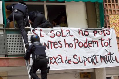 Los Mossos d'Esquadra entrando por la ventana en la vivienda que han desalojado en el barrio del Clot de Barcelona.