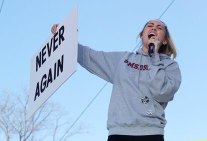 A cantora Miley Cyrus seguram um cartaz com o lema do protesto "Never Again" (Nunca Mais) na manifestação, em Washington.