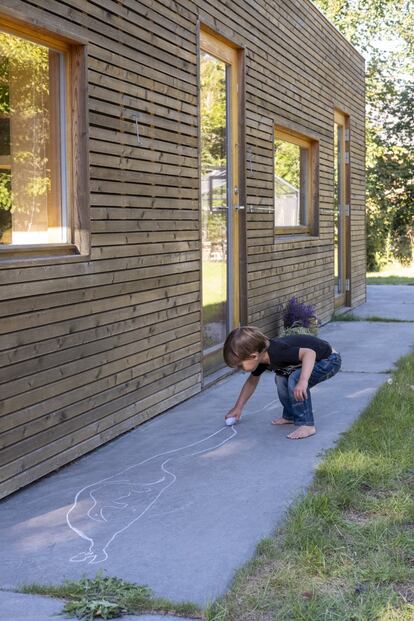 El exterior de la vivienda ha sido panelado con madera de alerce sin tratar que se oscurece con el paso del tiempo. Sembrado de plantas autóctonas como ciruelos, frambuesos y arándanos, el jardín precisa pocos cuidados. En la imagen, Noa Neri, hija de Jeppe y nieta de la dueña de la casa, dibuja con tiza sobre el hormigón que rodea la propiedad.