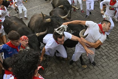 Varios mozos son embestidos por toros de la ganadería sevillana de Miura durante el octavo y último encierro, este lunes.