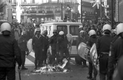 Agentes antidisturbios de la Policía Nacional apagan una fogata en la Puerta del Sol de Madrid durante la huelga general del 14-D contra la política económica del Gobierno.