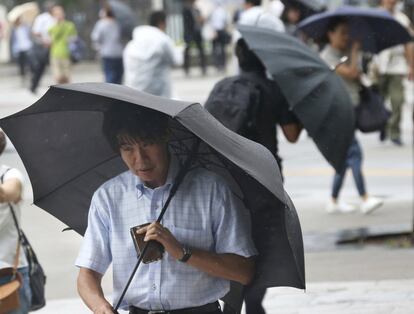 Pedestres tentam controlar seus guarda-chuvas em meio aos fortes ventos em Yokohama (Japão).