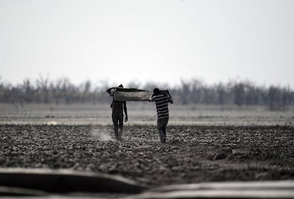 Pescadores cargan un bote por el lodo del lago Ngami, afectado por la sequía, en Maun (Botsuana), el 29 de agosto de 2019. El lago Ngami es una cuenca endorreica en Botsuana al norte del desierto de Kalahari.