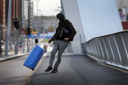 Un turista sujeta con fuerza su maleta mientras camina contra el fuerte viento para atravesar el puente Erasmus en Rotterdam (Holanda).