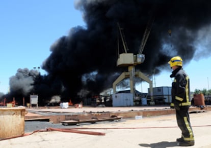 Un bombero observa los incendios causados por los trabajadores en los astilleros de Huelva.