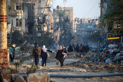 Un grupo de personas camina entre edificios derrumbados en el campo de refugiados de Al Maghazi, en el centro de Gaza, el 19 de enero. 