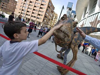 Un niño toca una de las maquetas utilizadas en el espectáculo <i>Caminando entre dinosaurios,</i> delante del Palacio de Deportes.