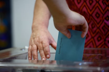 Una persona deposita su voto en la segunda vuelta de las elecciones parlamentarias anticipadas francesas, en un colegio electoral en París, Francia.