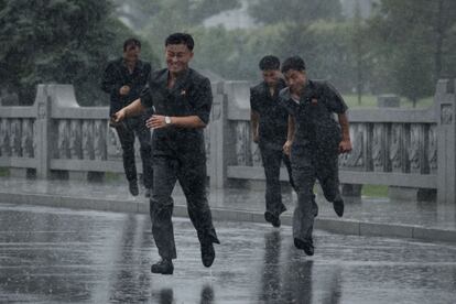 Un grupo de jóvenes corre bajo la lluvia mientras se dirige al palacio de Kumsusan durante el llamado 'Día de la Victoria', la fiesta nacional de Corea del Norte que conmemora el final de la Guerra de Corea, en Pyongyang (Corea del Norte).