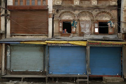 Un niño se asoma por la ventada de su casa durante el toque de queda en Srinagar, la zona de Cachemira controlada por India.