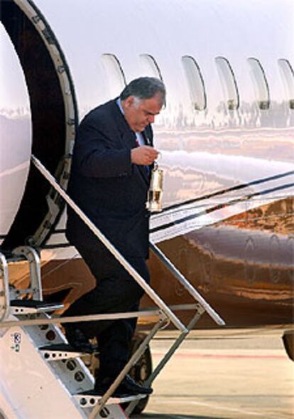 El director del recorrido olímpico, George Bolos, baja la llama olímpica del avión que la transportó desde Londres.