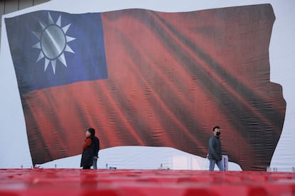 Un grupo de personas pasa junto a una imagen de una bandera taiwanesa durante un mitin de campaña del partido Kuomintang (KMT), en Taipéi, este viernes.