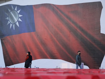 Un grupo de personas pasa junto a una imagen de una bandera taiwanesa durante un mitin de campaña del partido Kuomintang (KMT), en Taipéi, este viernes.