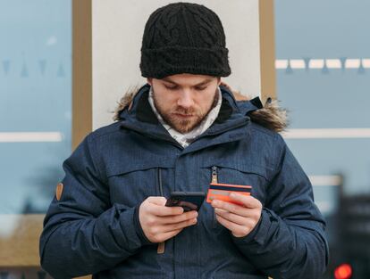 Un hombre utiliza una tarjeta bancaria en su móvil.