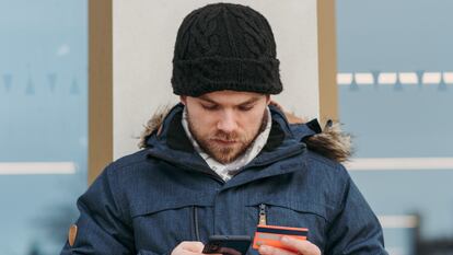 Un hombre utiliza una tarjeta bancaria en su móvil.