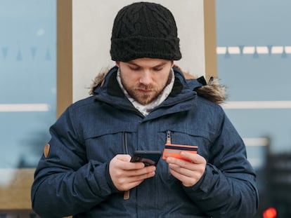 Un hombre utiliza una tarjeta bancaria en su móvil.