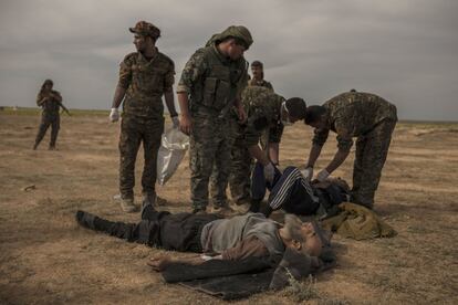 Soldados de las Fuerzas Democráticas Sirias asisten a civiles heridos durante los ataques aéreos en Baghouz.