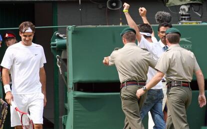 El personal de seguridad retira a un espontáneo durante un partido de Federer.