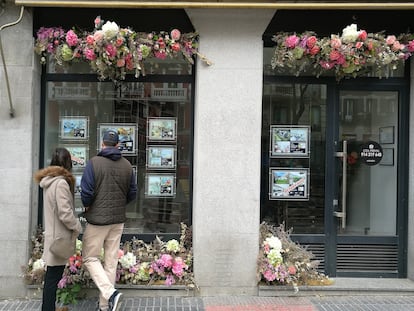 Una pareja ve las ofertas de apartamentos en el escaparate de una inmobiliaria en Madrid en 2021. 
