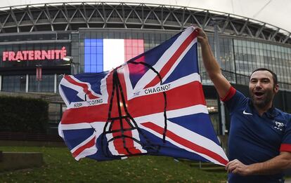 Un seguidor francés posa con una bandera del Reino Unido y el dibujo de la Torre Eiffel frente al estadio de Wembley antes del partido