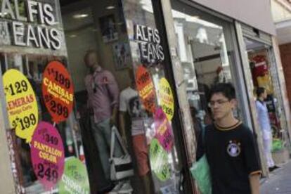 Un hombre camina frente a una tienda de ropa con avisos de promoción en el centro de Buenos Aires (Argentina). EFE/Archivo