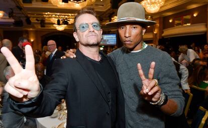 Los cantantes Bono y, a la derecha, Pharrell Williams.