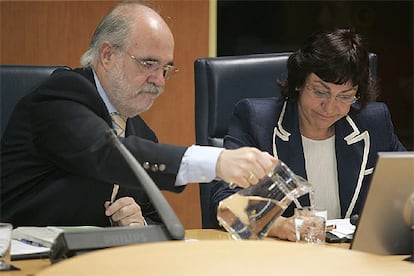 El parlamentario socialista Jesús Loza sirve agua a la consejera de Industria, Ana Aguirre, durante su comparecencia.