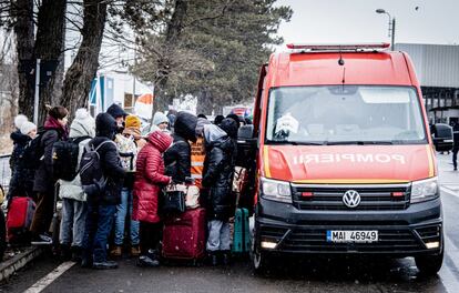 Refugiados procedentes de Ucrania caminan hacia los autobuses de los servicios de emergencia en la frontera entre Ucrania y Rumania, en Siret. En el lado ucranio del principal paso fronterizo con la localidad rumana de Siret, la cola de coches se extiende hasta 20 kilómetros, por lo que la travesía desde Kiev, que normalmente duraría ocho horas, puede ser ahora de dos días. Algunos recorren a pie por el arcén los últimos kilómetros, en paralelo al atasco, pese a que nieva y la sensación térmica a mediodía es de seis grados bajo cero.