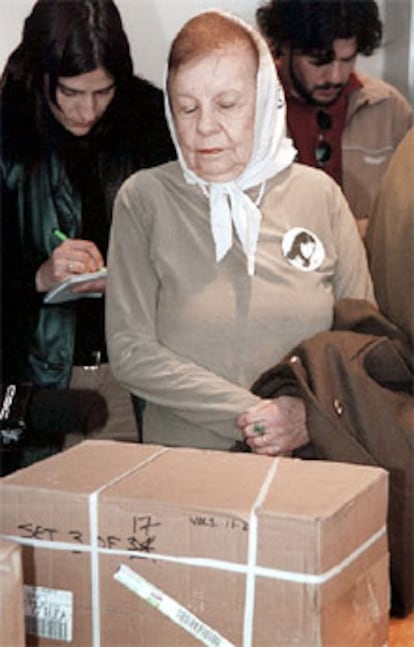 Una <b><i>madre de Mayo</b></i> mira una caja con documentos desclasificados.