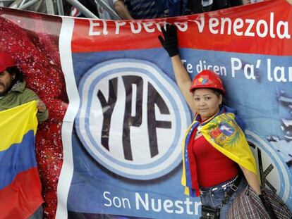 Unos venezolanos posan junto al logotipo de la petrolera YPF durante un acto en Buenos Aires, Argentina.