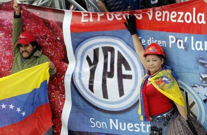 Unos venezolanos posan junto al logotipo de la petrolera YPF durante un acto en Buenos Aires, Argentina.