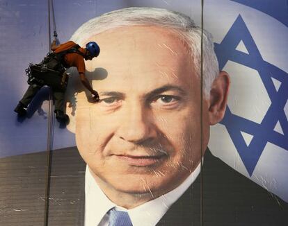 Un trabajador coloca en Tel Aviv un cartel de la campa&ntilde;a electoral de Netanyahu.